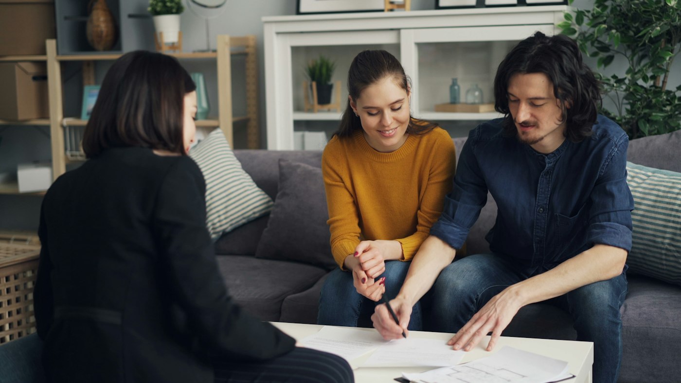 three people sitting on a couch looking at a piece of paper
