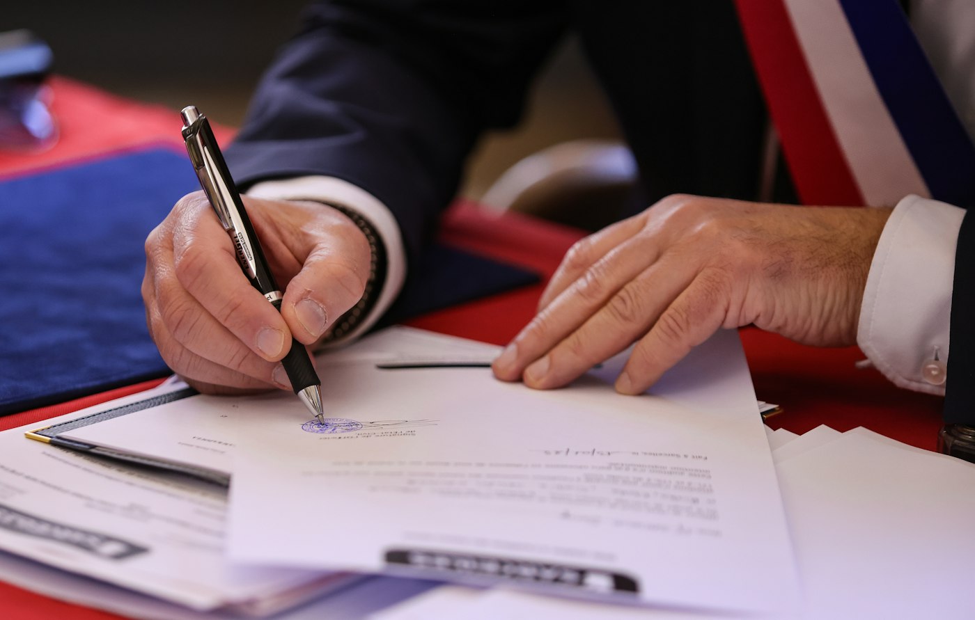A person signs a document with a pen